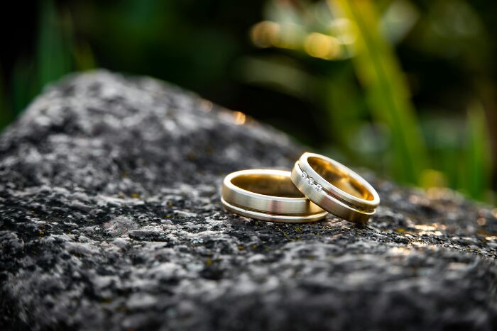 Wedding rings on a rock with natural background, symbolizing wild and sad wedding stories.