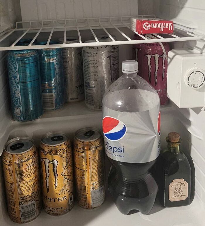Fridge interior with cans of energy drinks, Diet Pepsi, and cigarettes; example of chaotic dude fridge.