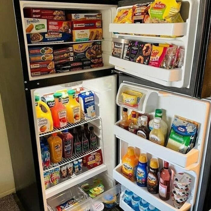 A 'dude fridge' packed with frozen meals, juices, sauces, and dairy products.