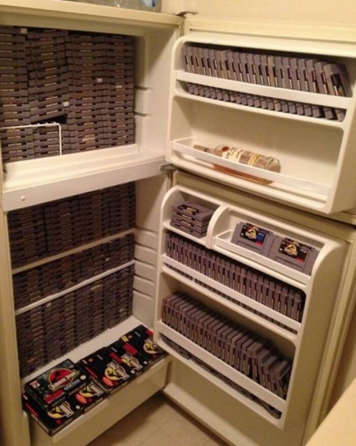 A fridge filled with rows of video game cartridges, showcasing a typical 'dude fridge' from a chaotic Instagram account.