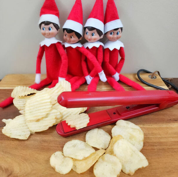 Four Elf On The Shelf dolls behind a hair straightener making homemade potato chips on a wooden surface.