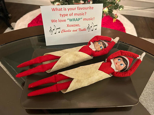 Two Elf On The Shelf dolls wrapped in tortillas on a tray with a note about loving wrap music, creative mischief idea.