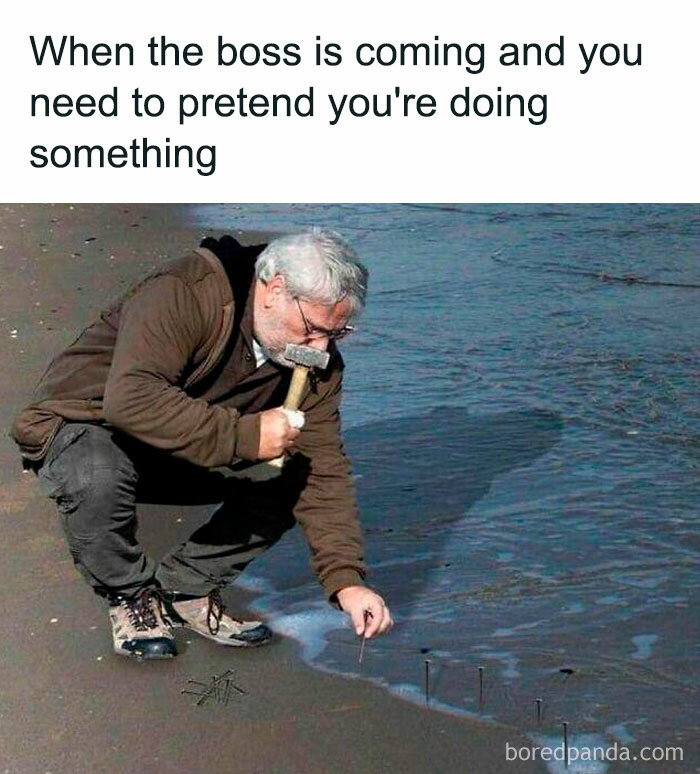 Man on a beach pretending to work by hammering nails into the sand; perfect meme for a coffee break laugh.