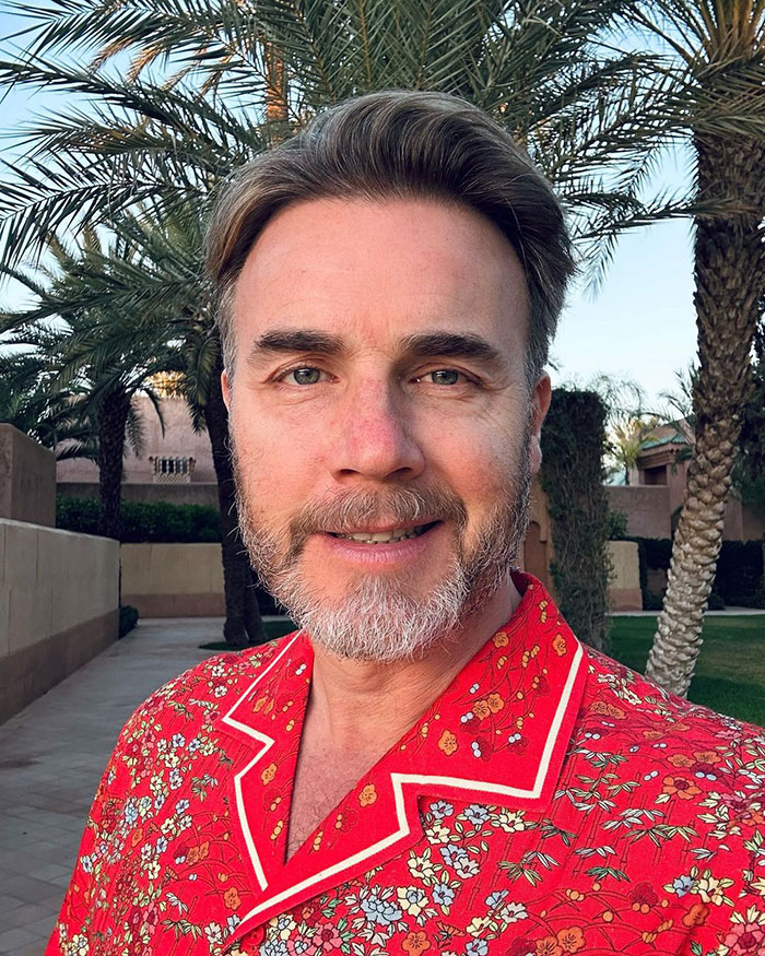 Man in a colorful shirt with palm trees in the background; related to British star and memes.