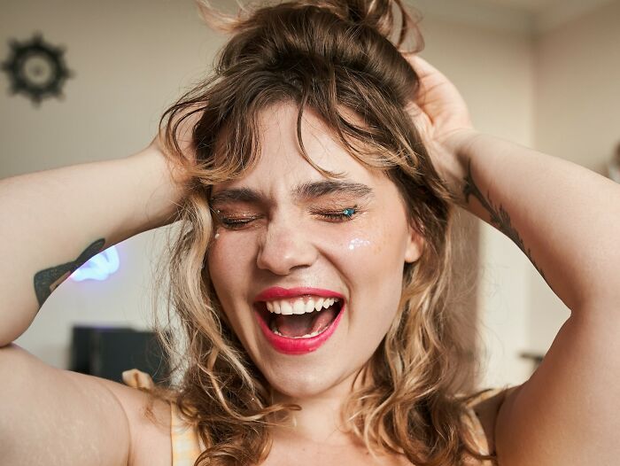 Woman smiling with hands in hair, representing confidence despite being outnumbered.