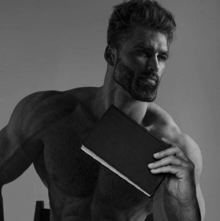 Grayscale image of muscular man, Giga Chad meme, holding a book with a thoughtful expression.