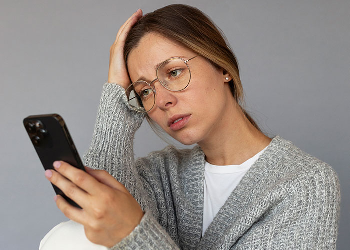 Woman looking worried at phone after receiving unexpected message on the weekend.