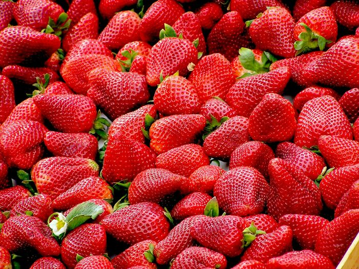Fresh strawberries piled together, evoking happiness with their vibrant red color and sweet aroma.