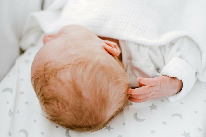 A sleeping baby under a white blanket, symbolizing pure happiness and comfort.