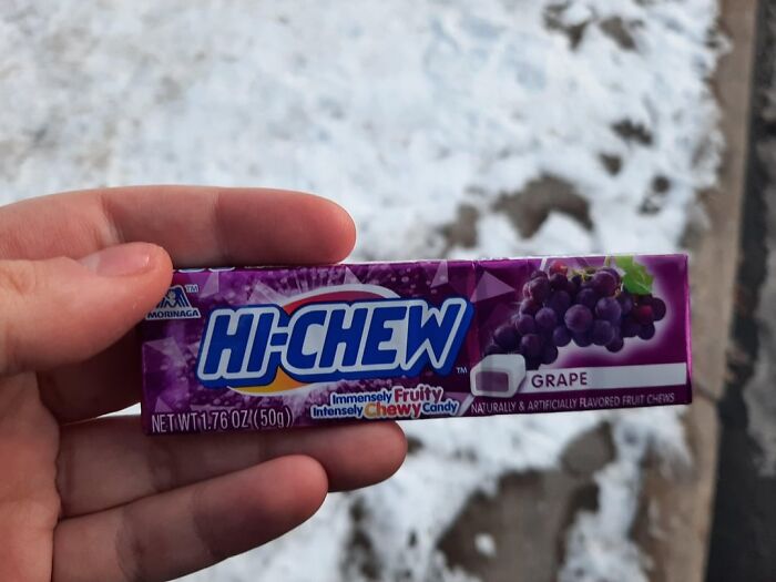 Hand holding grape-flavored Hi-Chew candy with snowy background, linked to smell happiness discussion on Reddit.