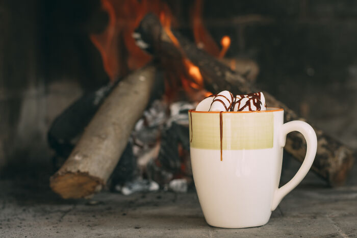Mug of hot chocolate near a cozy fire, evoking smell-happiness-reddit vibes.