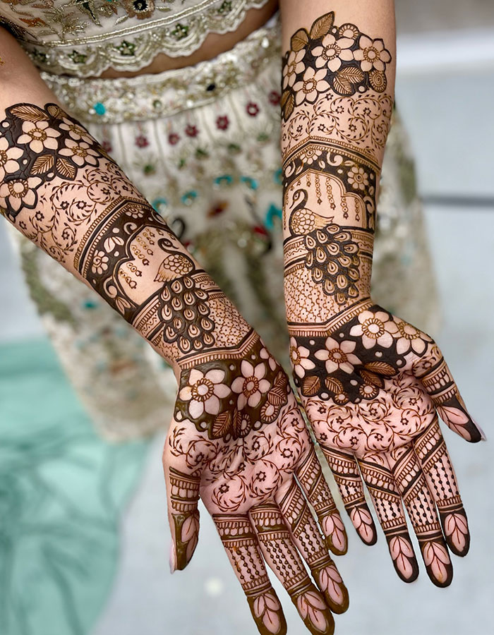 Intricate henna tattoo design on hands with floral and peacock patterns, showcasing stunning and detailed artwork.
