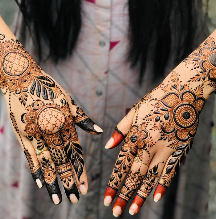 Intricate henna tattoo designs on hands featuring detailed floral patterns.