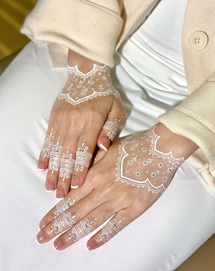 White henna tattoo design on hands with intricate patterns, showcasing stunning henna artistry.