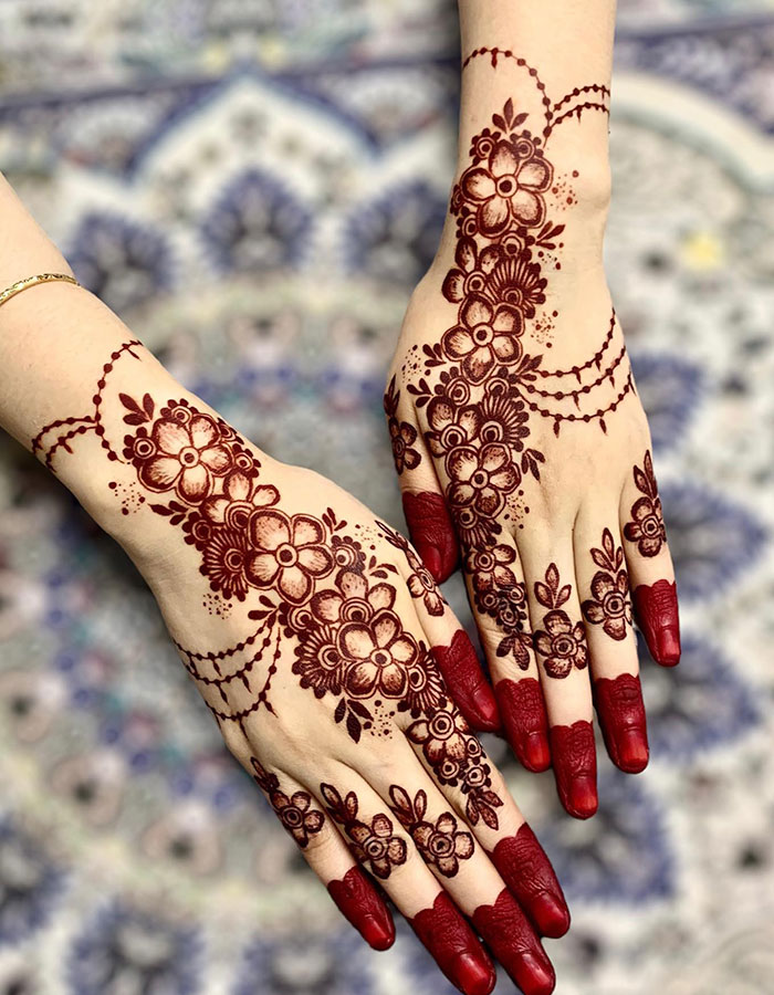Intricate henna tattoo design on hands with floral patterns, showcasing traditional art and style.