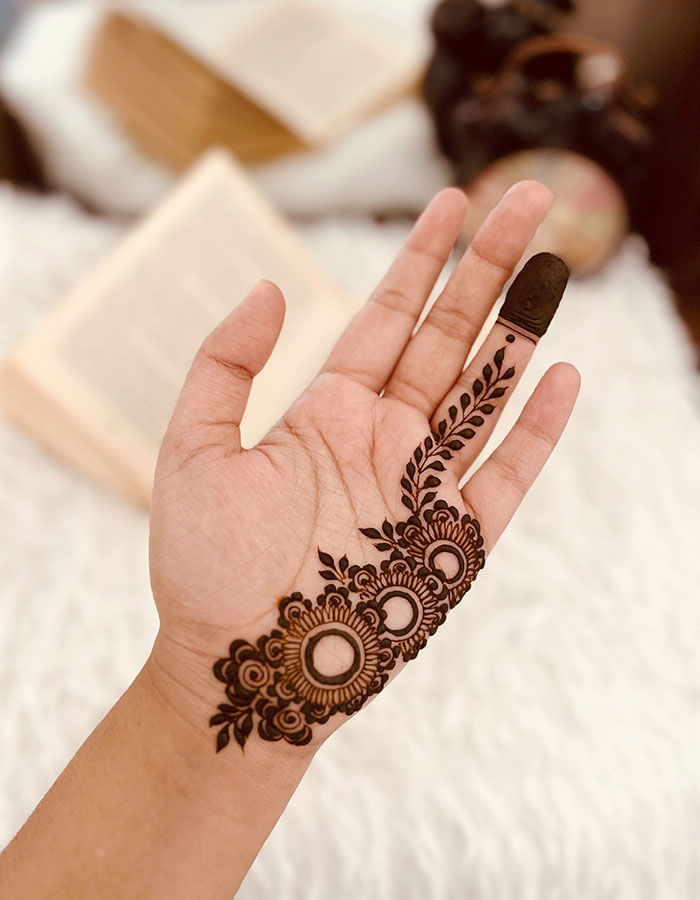 Henna tattoo design on a hand, featuring intricate floral patterns and leaf motifs.