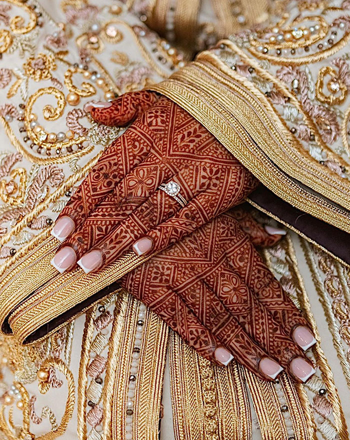 Intricate henna tattoo on hands with ornate gold fabric, showcasing stunning design ideas.