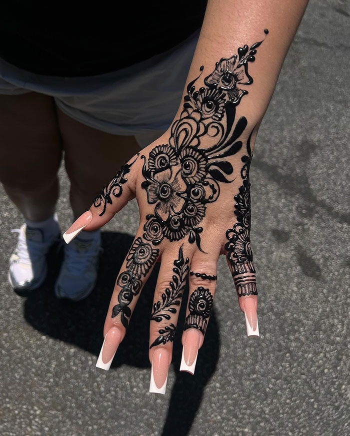 Intricate henna tattoo design on a hand with floral and geometric patterns.