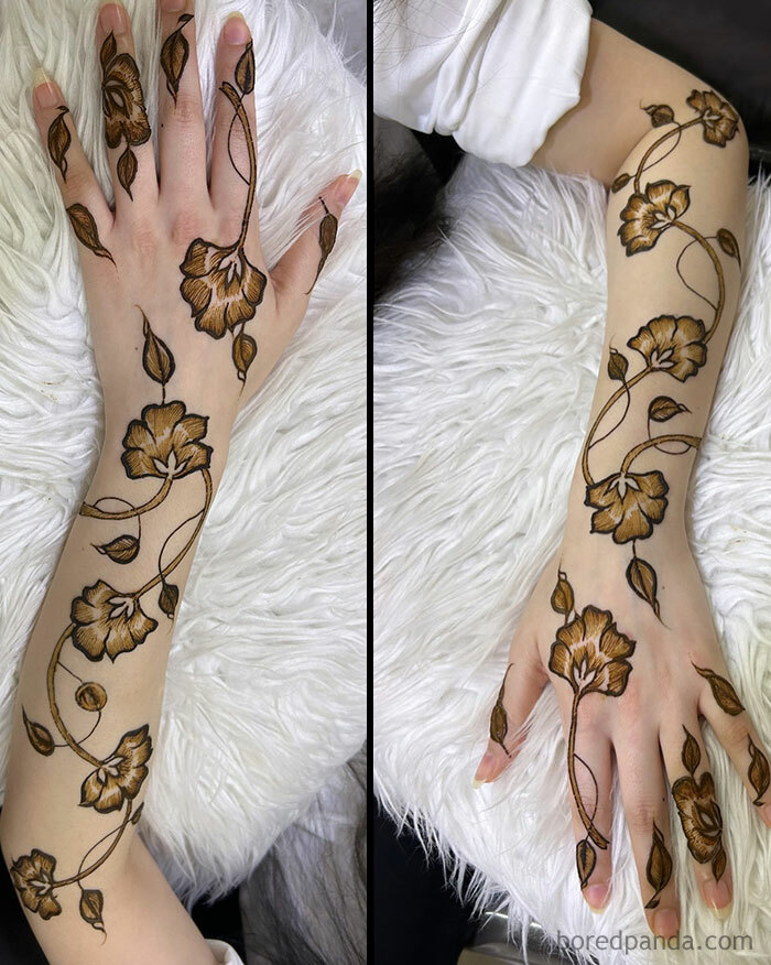 Floral henna tattoo on a forearm and hand, showcasing intricate, stunning designs on a white fur background.