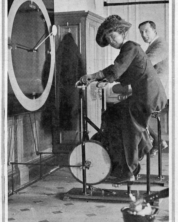 A Man And A Woman Riding On Cycling Machines In The First Class Gym Onboard Rms Titanic. Ca. 1911