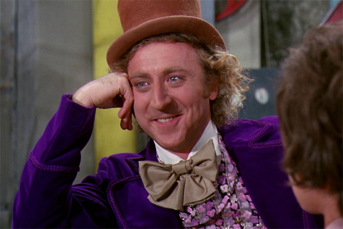 Actor in a purple suit with a top hat, perfectly embodying a character role.