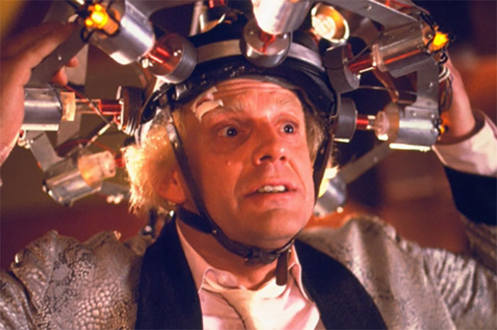 Actor in eccentric role, wearing a futuristic device on head, embodying character charisma flawlessly.