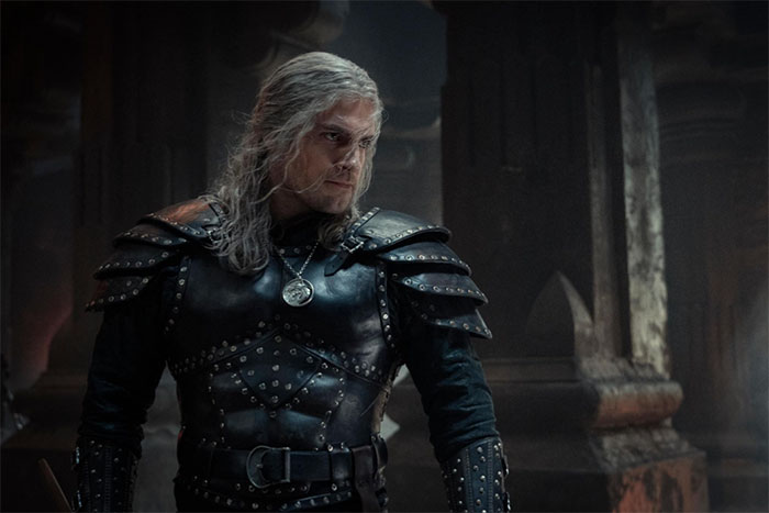 Actor in detailed medieval armor standing in a dimly lit, intricate stone setting; nailed a role perfectly.