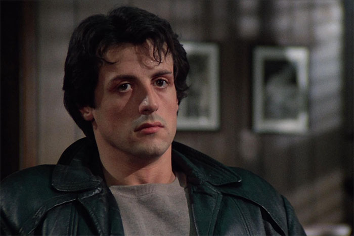 Actor in a leather jacket, sitting in a dimly lit room, showcasing flawless acting skills.