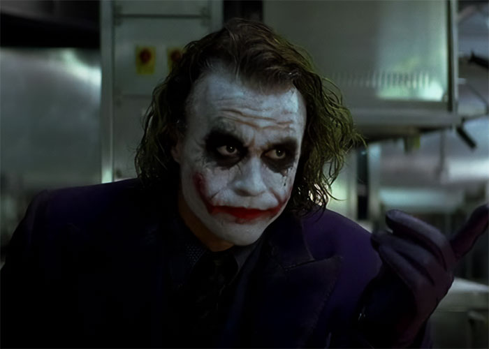 Actor in iconic role with smeared makeup and purple suit, embodying a memorable performance.