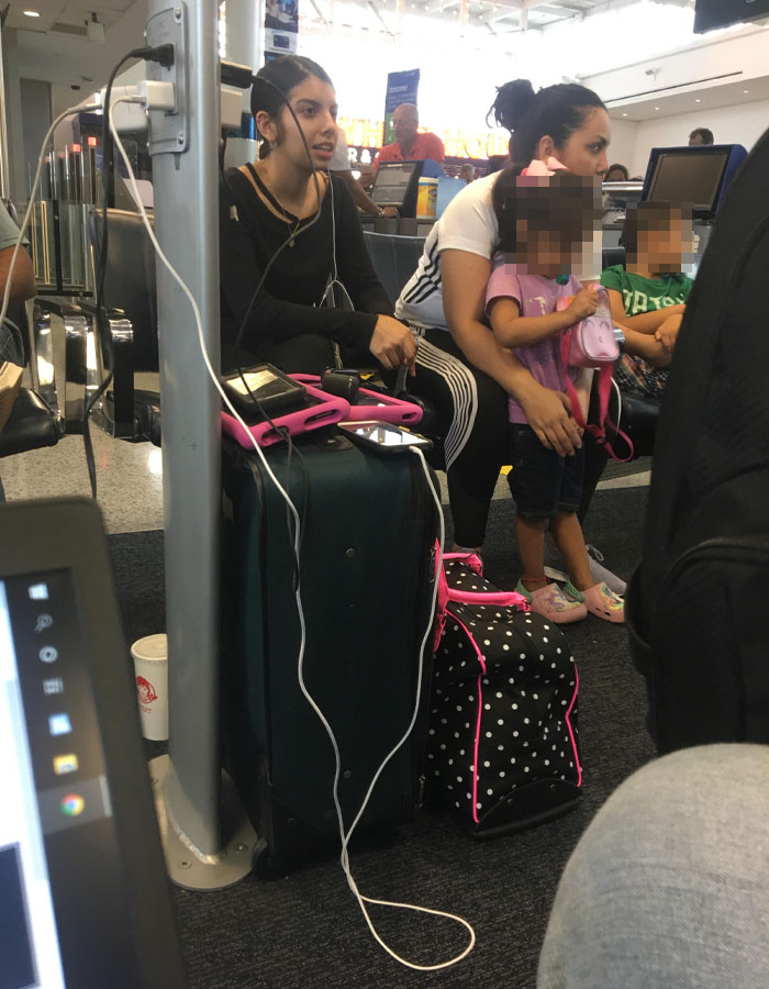 Passengers sitting with luggage and electronics at an airport, depicting typical annoying plane passenger behavior.