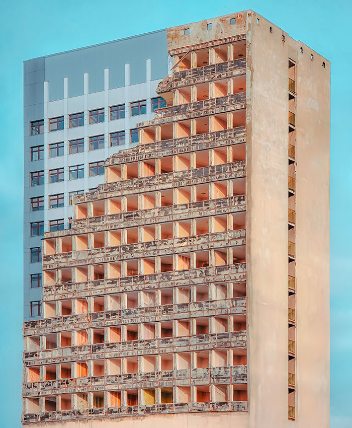Unique building with eroded facade, showcasing interesting non-Photoshopped architectural design against a blue sky.