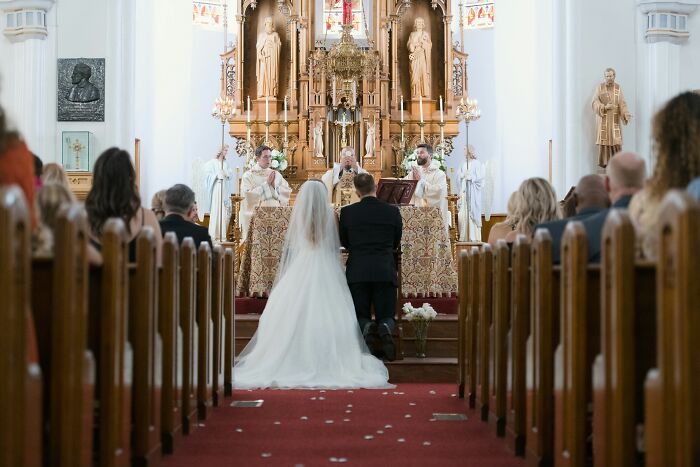 Bride and groom kneeling at the altar during a wedding ceremony in a church.
