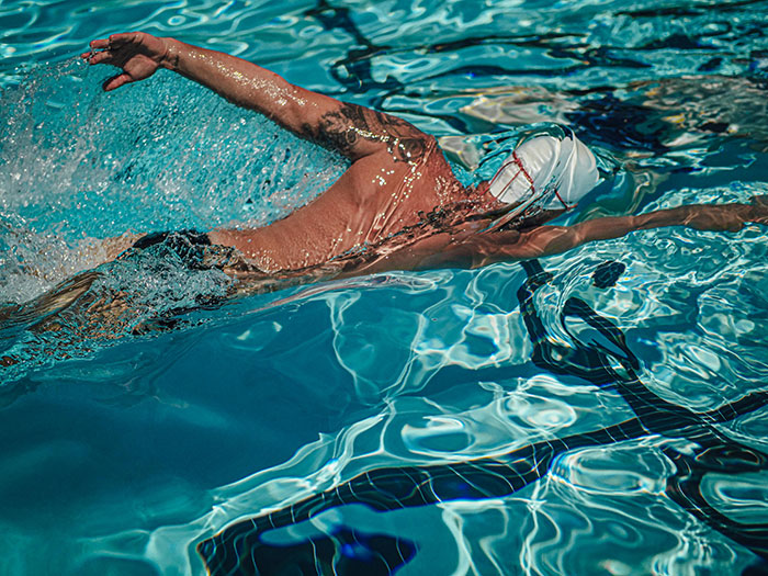 Adult swimming in a pool, demonstrating essential life skills.