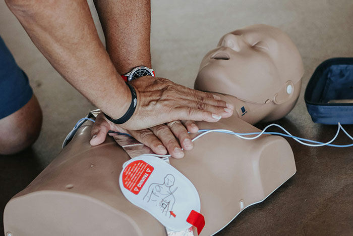 Hands performing CPR on a dummy, illustrating essential life skills training for adults.