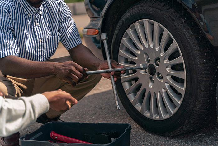 Changing a car tire, demonstrating essential life skills for adults.