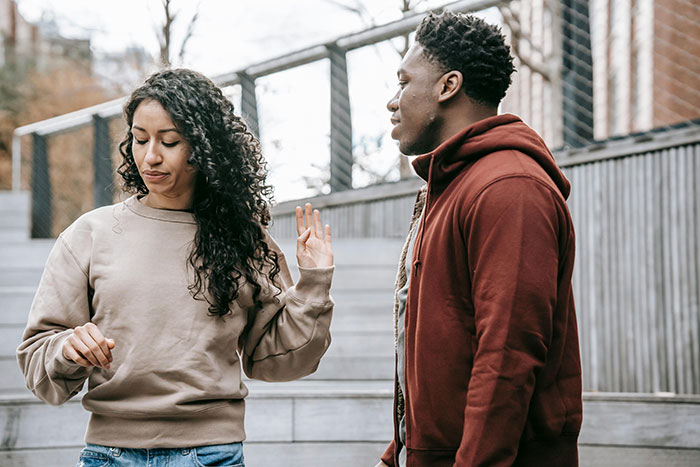 Two adults in casual clothes having a conversation on outdoor steps, highlighting essential life skills.