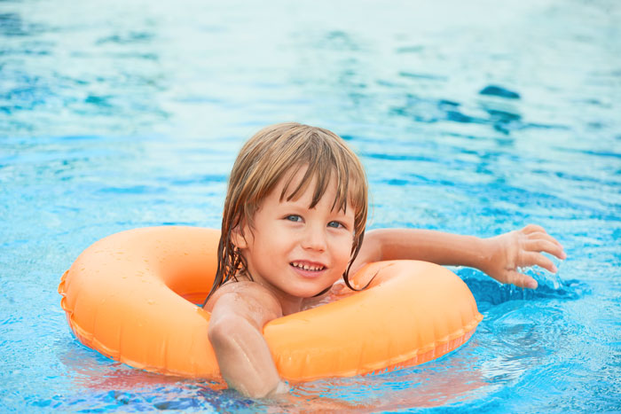 Child in orange float enjoying solo time in pool. Child in orange float enjoying solo time in pool.