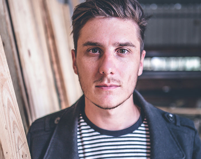 A man in a striped shirt standing indoors, linked to a story about a woman running away from a date.