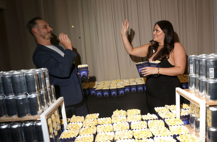 Couple enjoying popcorn at a social event, surrounded by snacks and drinks, highlighting "Love Is Blind" couples' activities.