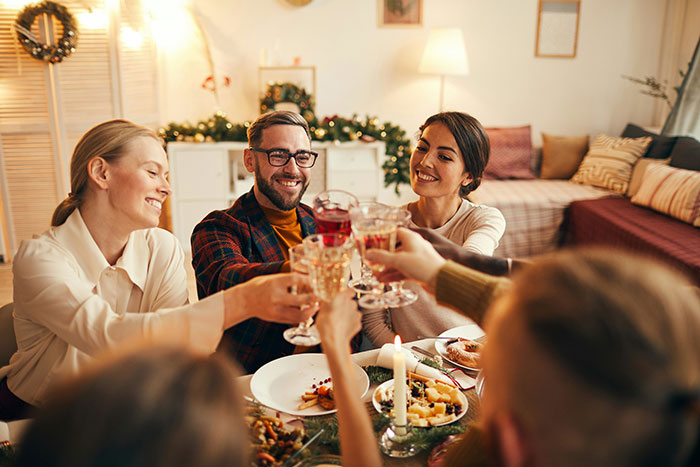People toasting drinks at a festive dinner gathering, creating a cheerful and celebratory atmosphere.