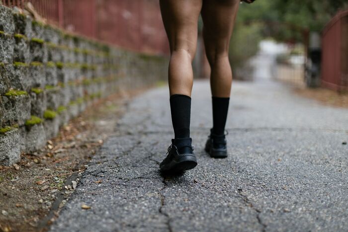 Person walking alone on a paved path, wearing black socks and shoes, illustrating the theme of outnumbered decisions.