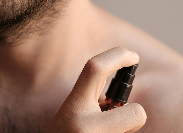 Close-up of a shirtless person applying spray, relating to dark secrets in the Hollywood entertainment industry.