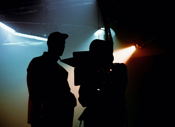 Silhouettes of filmmakers on a set, capturing Hollywood's entertainment industry atmosphere.