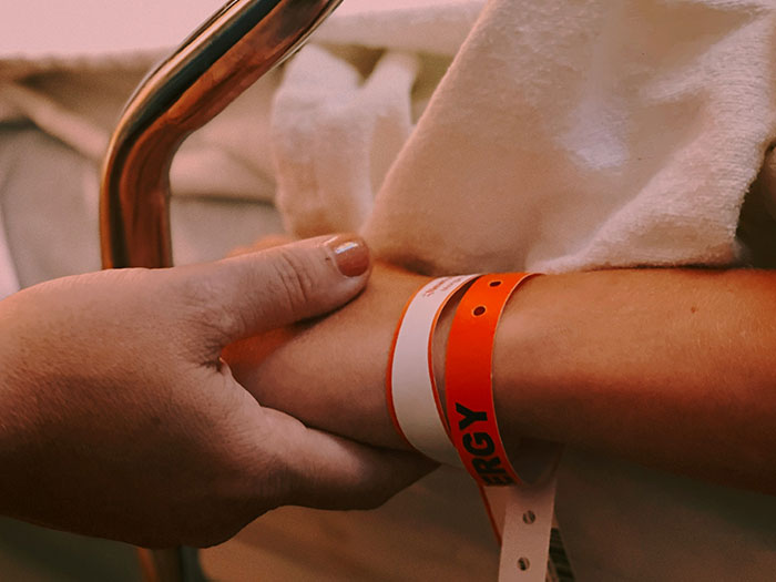 "Person holding hospital wristband, symbolizing exposure of Hollywood secrets."