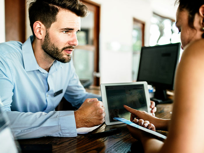 Man discussing Hollywood secrets in an office setting, with a tablet and computer on the desk.