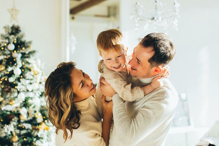 Happy family with a child enjoying time together near a Christmas tree.