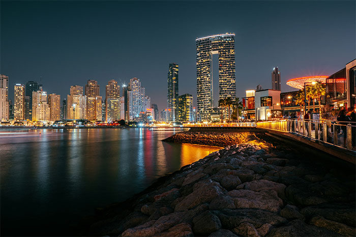 Night view of a city skyline by the water, highlighting hyped travel destinations.