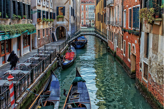 Venice canal with gondolas and an arched bridge, illustrating hyped travel destinations and potential disappointment.