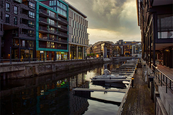 Canal with boats in an urban setting, surrounded by modern buildings, possibly a hyped travel destination.