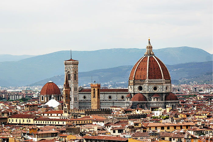 Florence Cathedral, a hyped travel destination, viewed from afar with cityscape and mountains in the background.